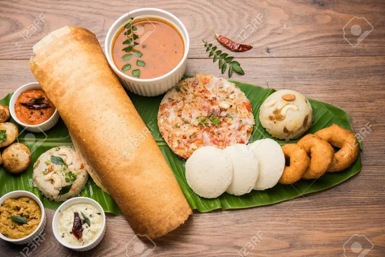 Idli, dosa, and vada on banana leaf with their respective sauces