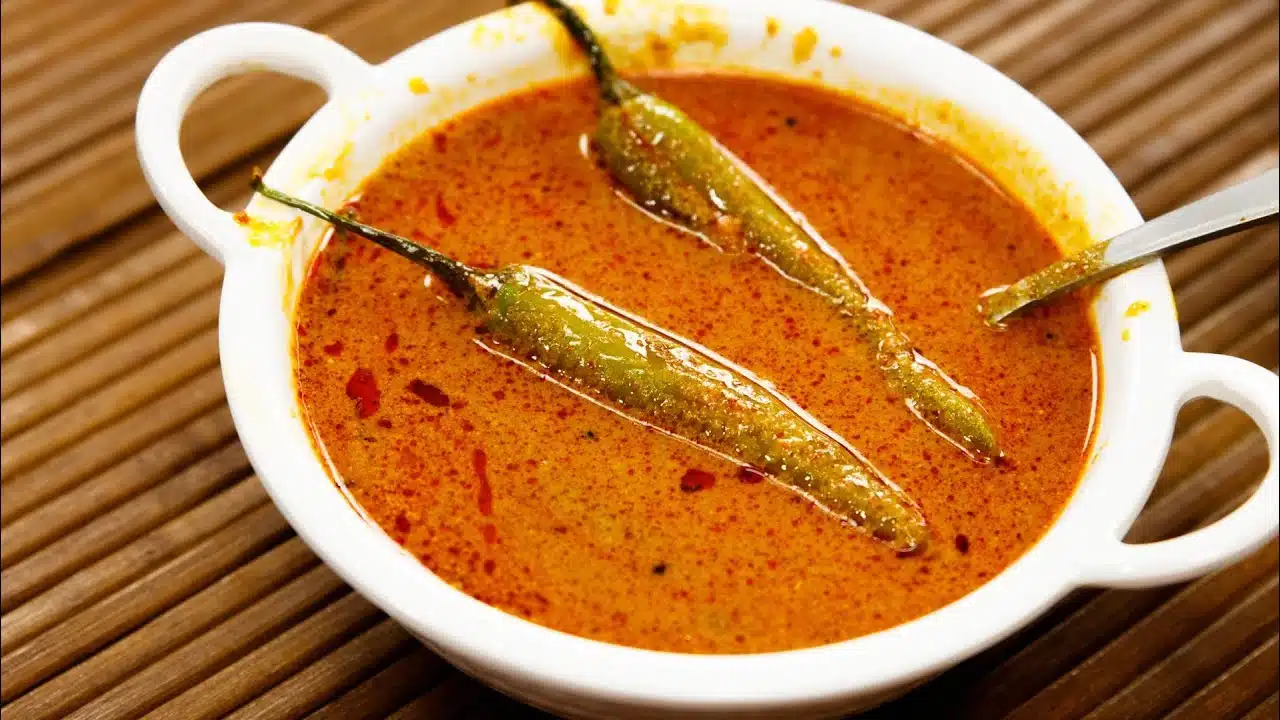 Mirchi ka salan in a bowl with spoon and two chillies